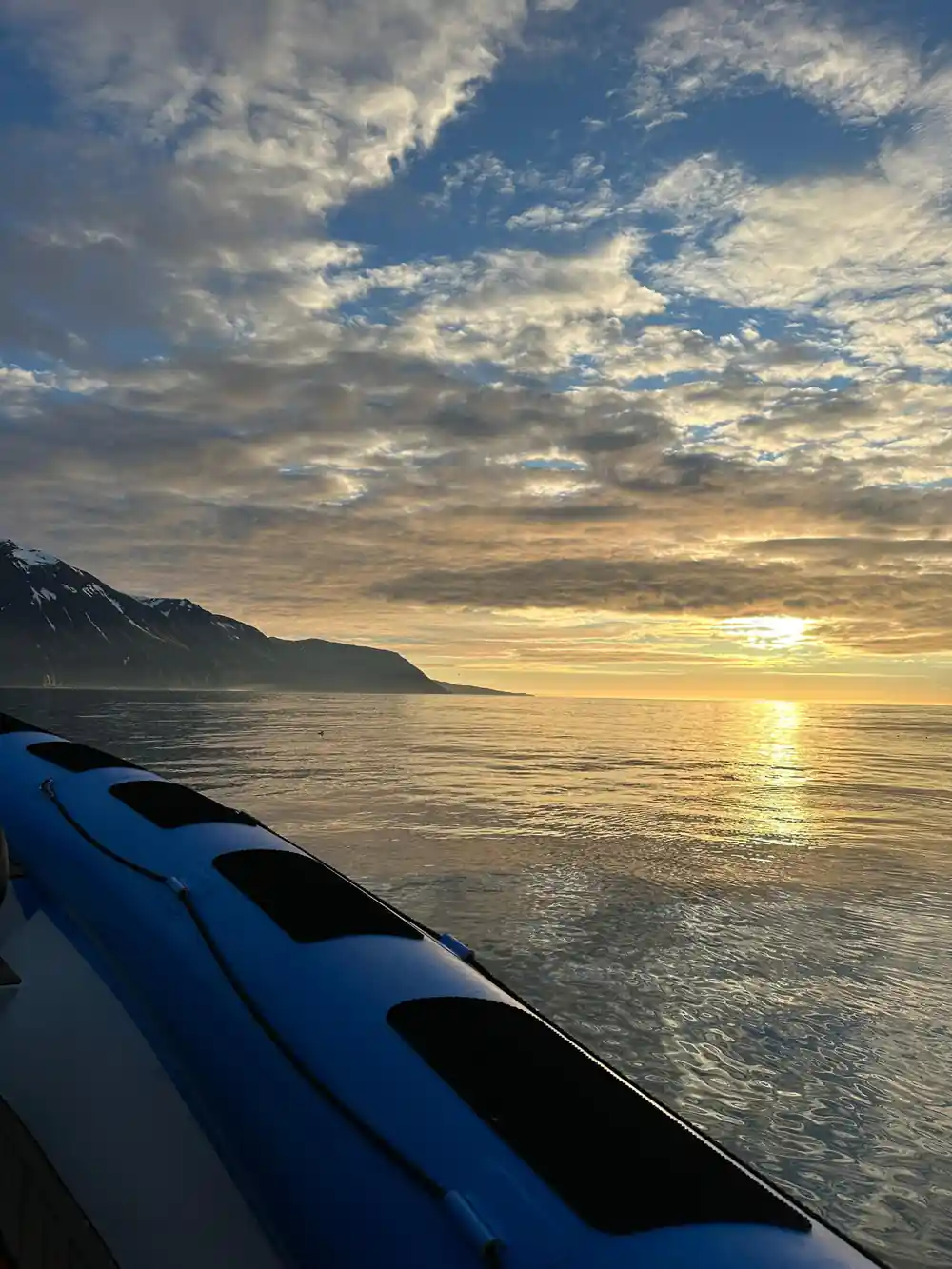 Blue kayak in foreground, sunset over mountain and sea