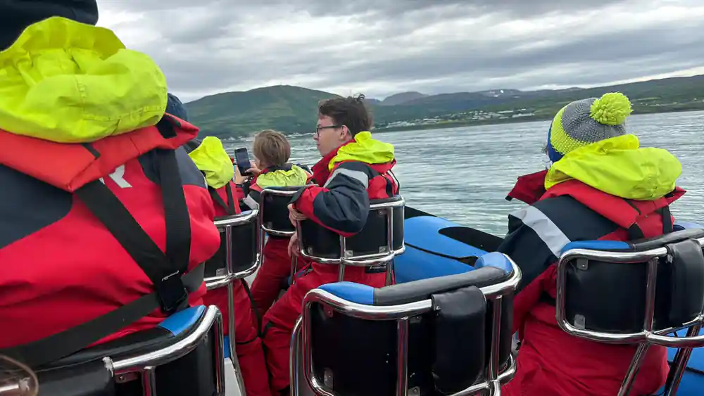 Group of tourists in safety gear on inflatable boat at sea