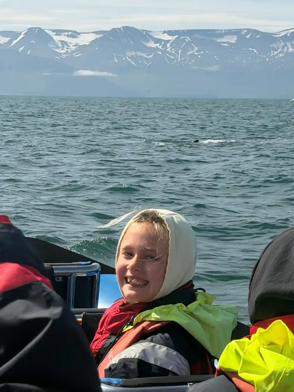 Person smiling on boat with snow mountains behind